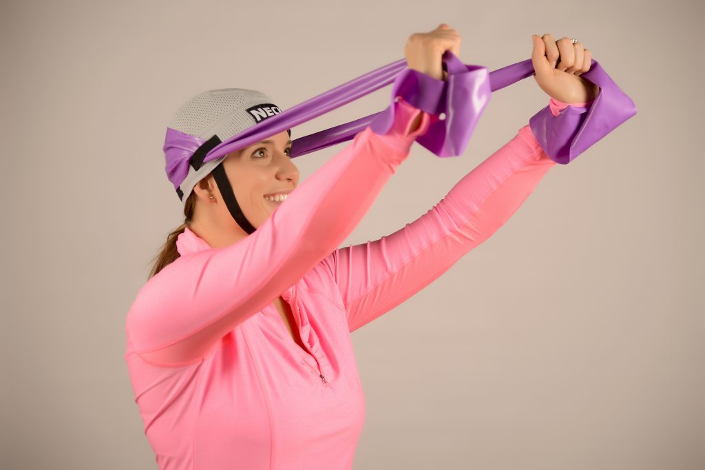 A woman in a pink shirt is holding a purple strap.