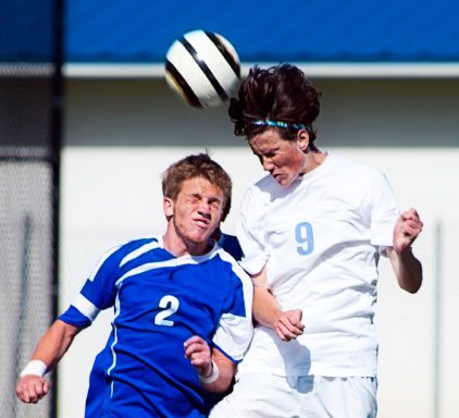 Two soccer players jump for the ball during a game.