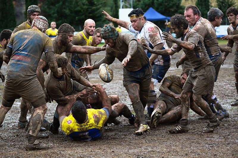 A group of men playing rugby in a muddy field.