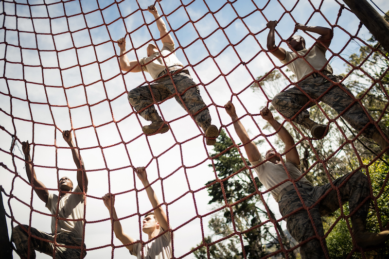 A group of men are climbing a net.